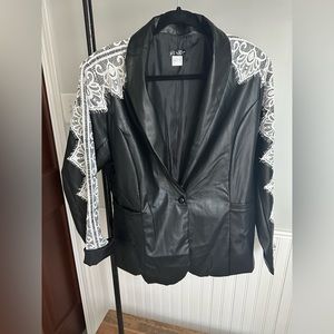 Faux leather jacket with lace stitching over shoulders and down arms.